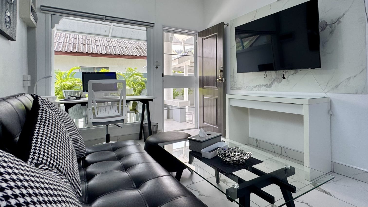 Living room with a black sofa, glass table and wall-mounted television